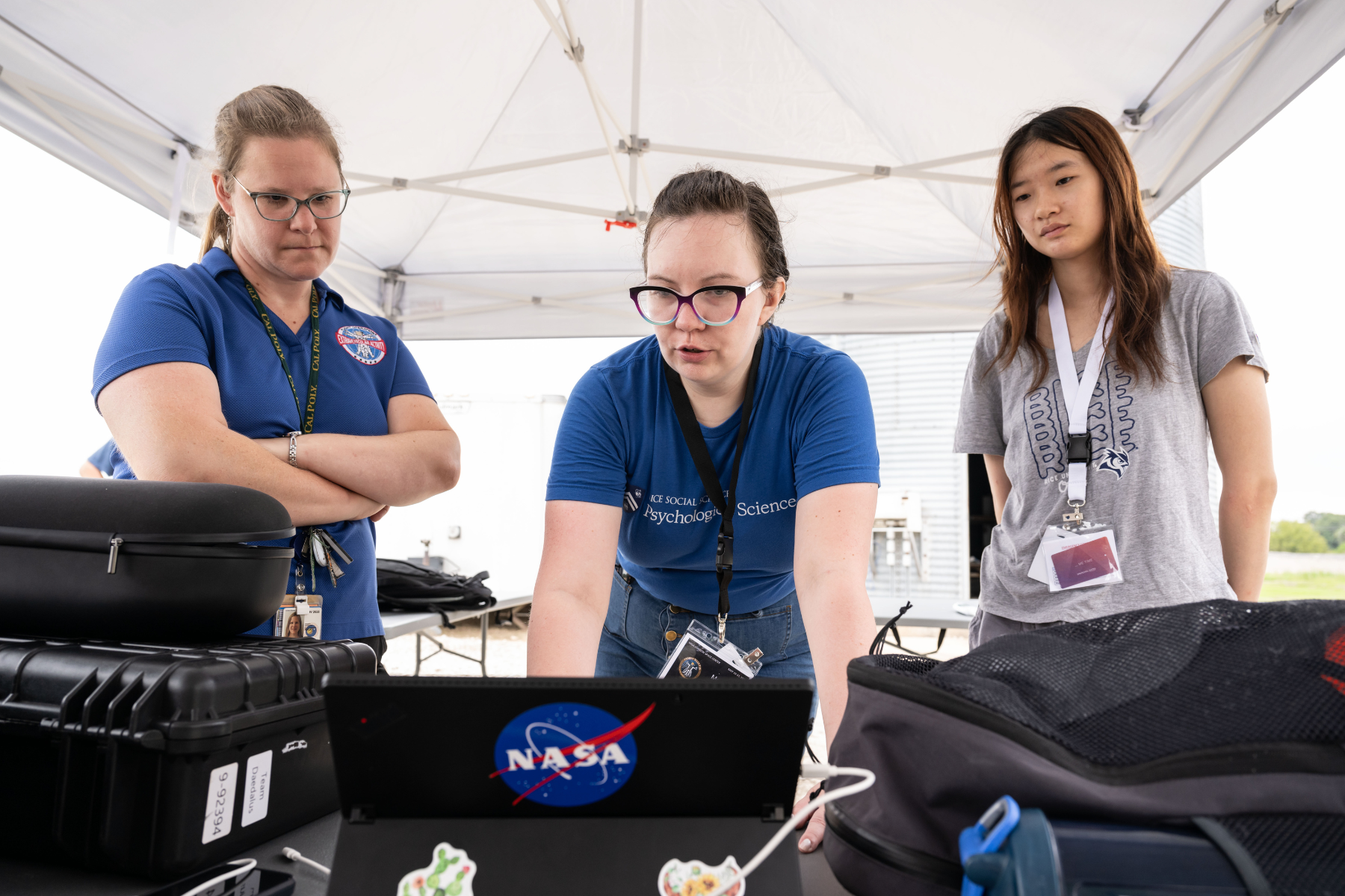 Three people standing over a laptop