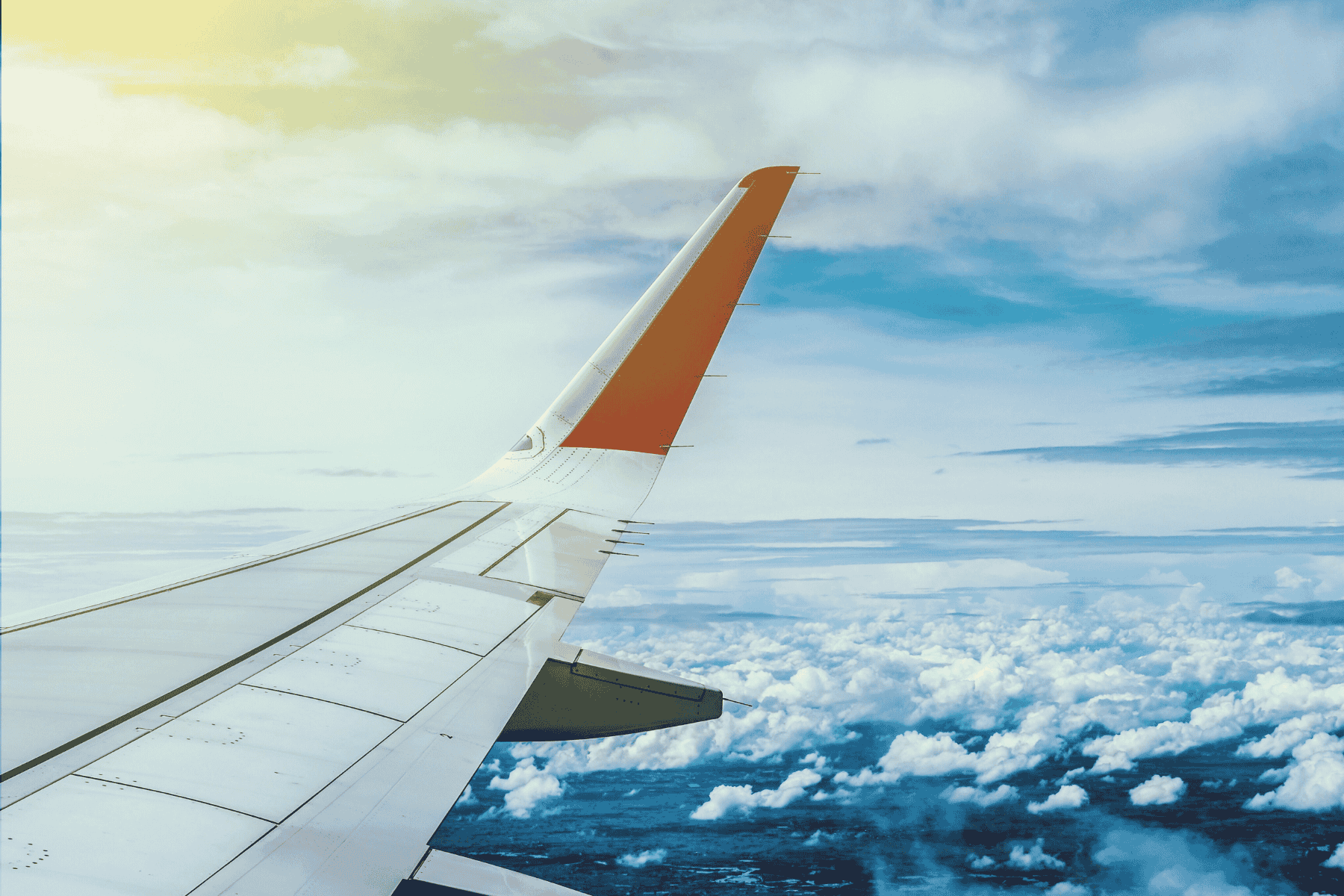 The wing of an airplane over clouds