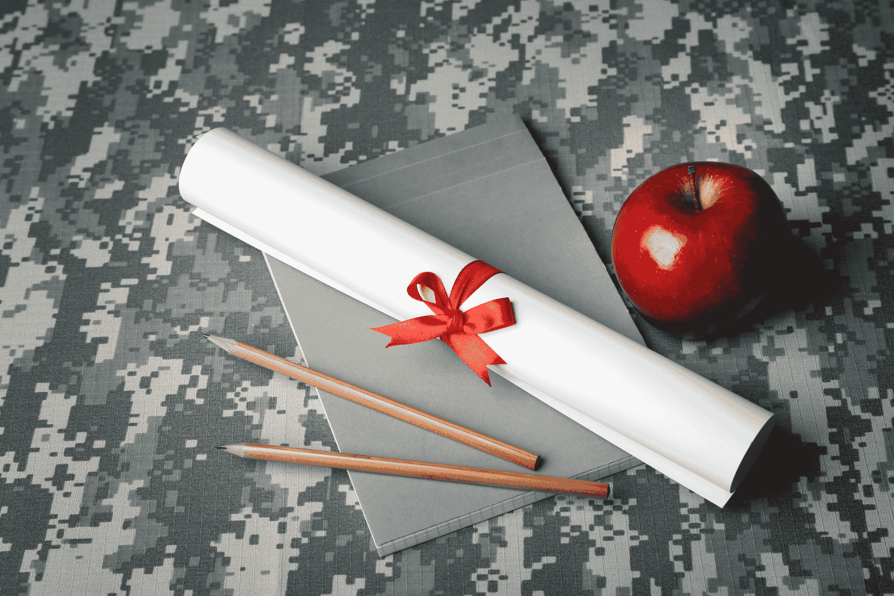 diploma, notebook, pencils, and apple over a camo background. Rice University Department of Psychological Sciences